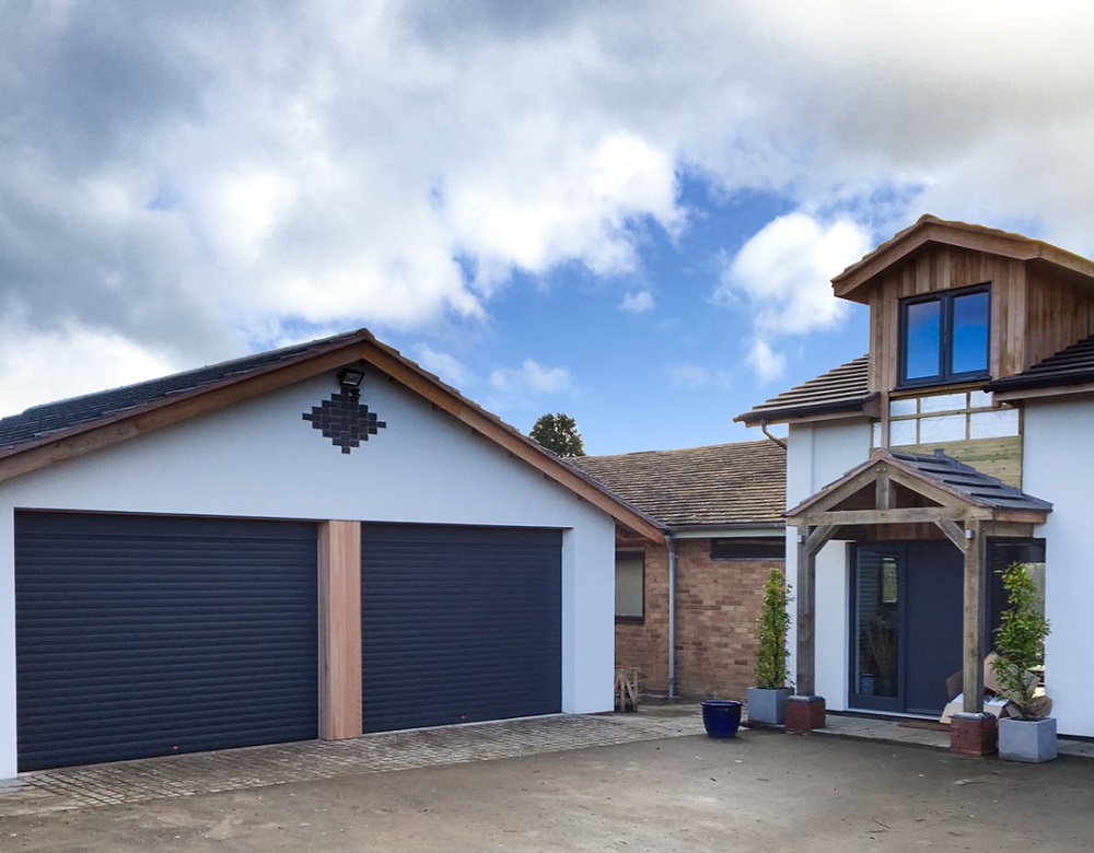 Birkdale anthracite grey insulated roller doors fitted to a white rendered double garage.