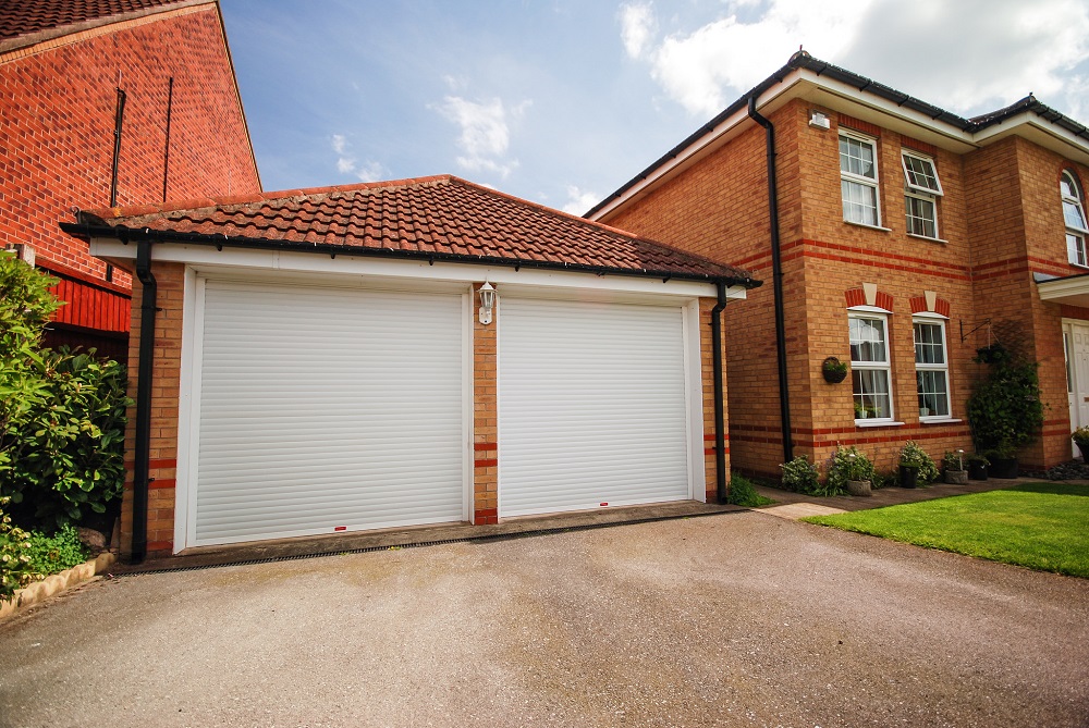 cheap insulated roller doors in white fitted side by side within a large georgian style double garage.