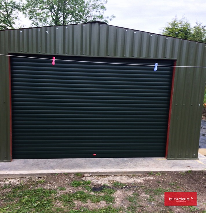 Black insulated industrial roller shutter fitted to a small scale industrial building