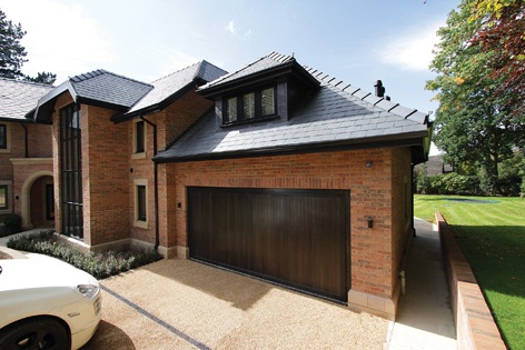 Woodrite Chalfont up and over wooden garage door with a dark stain and matching frame.