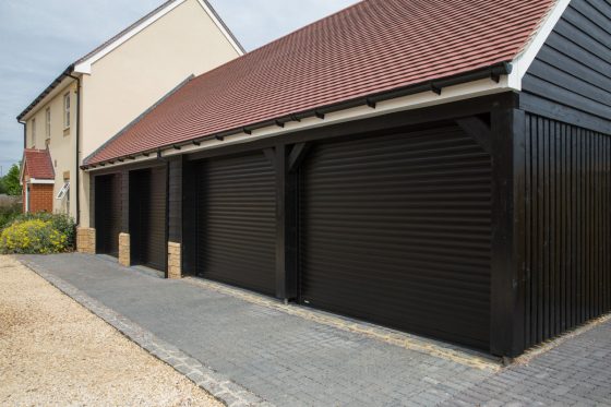 Triple garage fitted with 3 electric roller doors finished with a black powder coated paint.