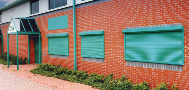 Dark green powder coated security window shutter fitted to a school building to secure classrooms from theft and vandalism.