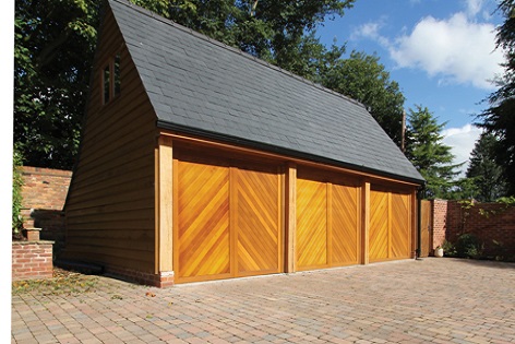 Chevron boarded up and over wooden garage doors fitted side by side in a large detached triple garage