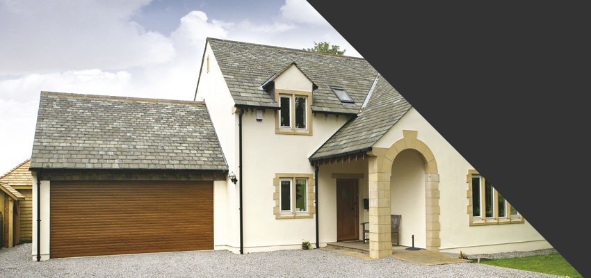 Golden Oak roller shutter garage door fitted to a white rendered detached house